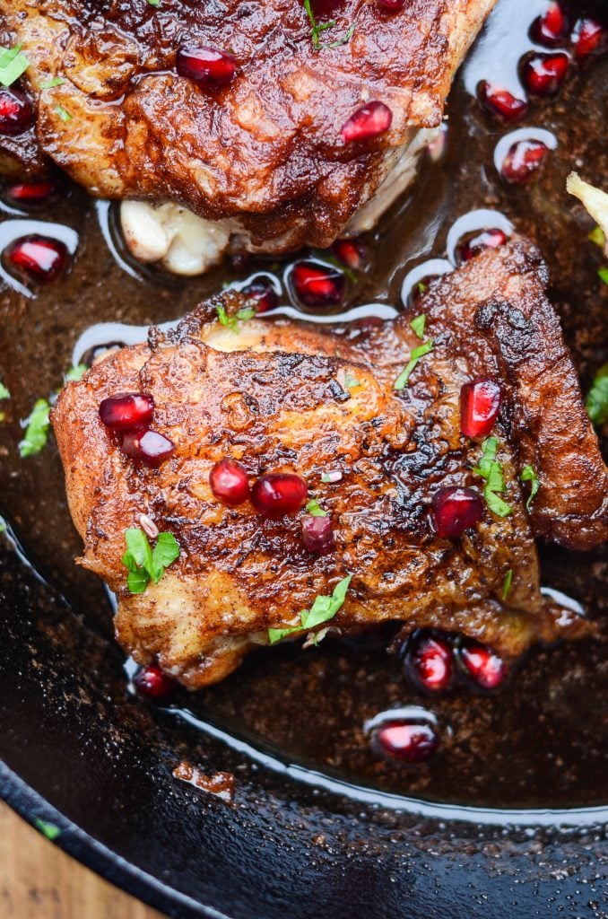 one pan fried cinnamon rubbed chicken thigh with pomegranate seeds on top