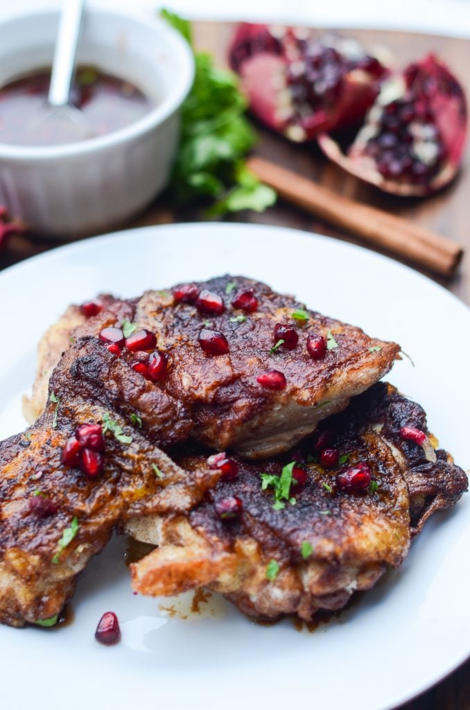 a plate of one pan chicken thighs topped with pomegranate seeds