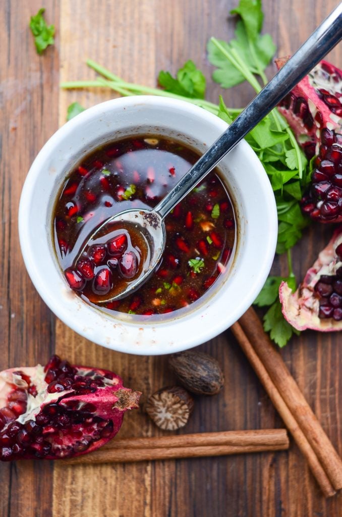 A ramekin of pomegranate sauce with a spoon in it