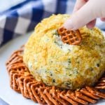hands dipping a pretzel into a Fire Roasted Jalapeno Cheese Ball