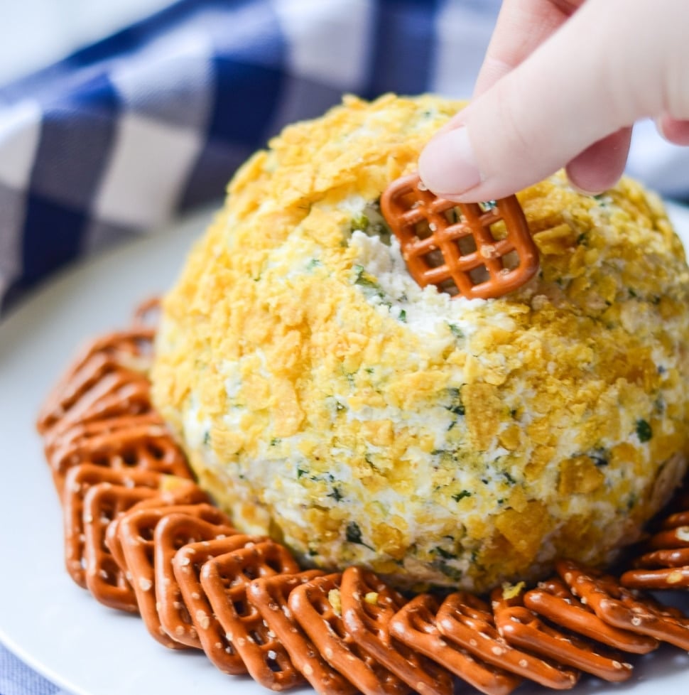 hands dipping a pretzel into a Fire Roasted Jalapeno Cheese Ball