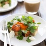 Lime Cured Salmon, Egg and Avocado Muffin on white plate with silverware and coffee