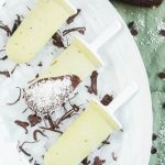 three popsicles on a white plate next to chocolate shavings