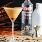 coffee cocktail in a martini glass with bottle of smirnoff and jigger behind it