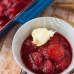 a bowl of roasted strawberries with cream next to blue pan of roasted strawberries