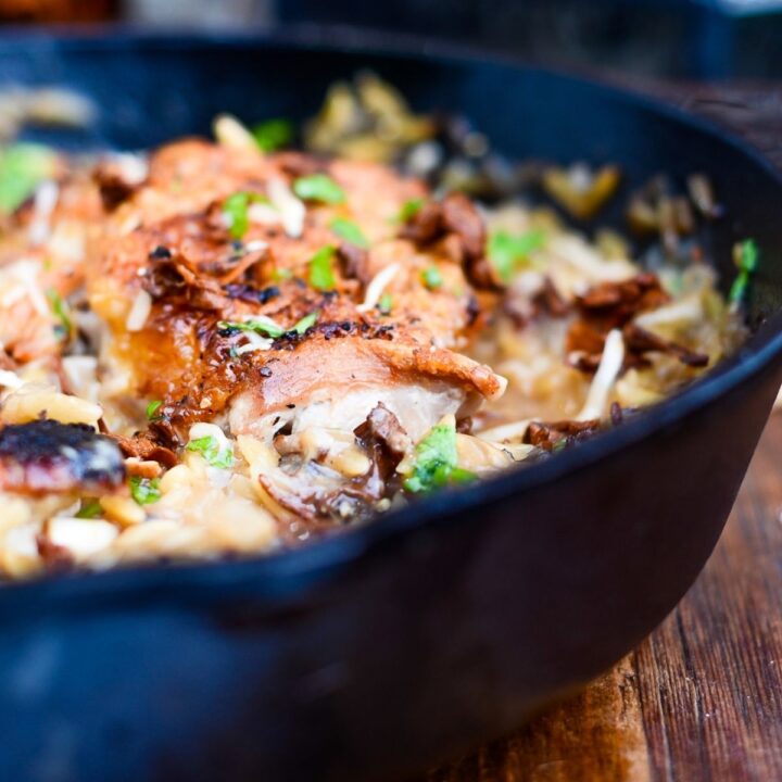 A black bowl filled with cooked chicken, and mushroom's