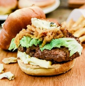 Roasted Garlic Burger with Cambozola on a wooden cutting board next to french fries