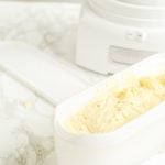 a white tub of homemade custard ice cream in front of an ice cream maker
