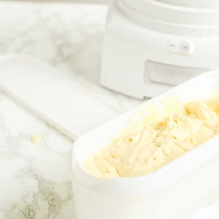 a white tub of homemade custard ice cream in front of an ice cream maker