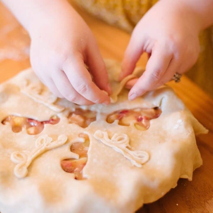 A pair of hands handles raw dough on a pie