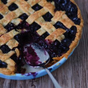 A pie server sitting in the opening of a missing piece of spiced blueberry pie.