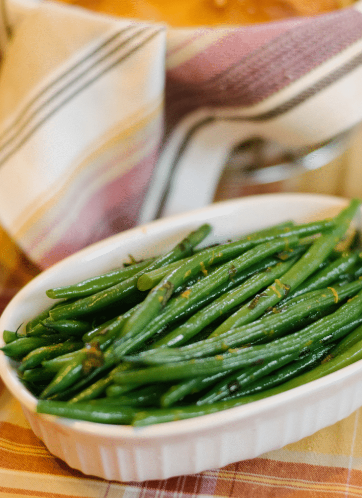 A small serving dish of haricots verts on an autumnal tablecloth.