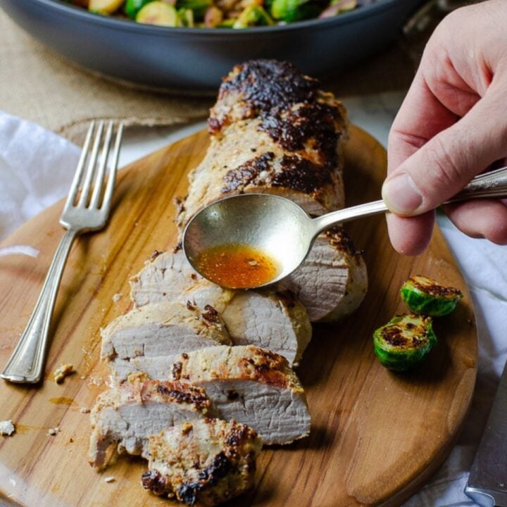 Cooked pieces of tenderloin with a spoon filled with a orange liquid