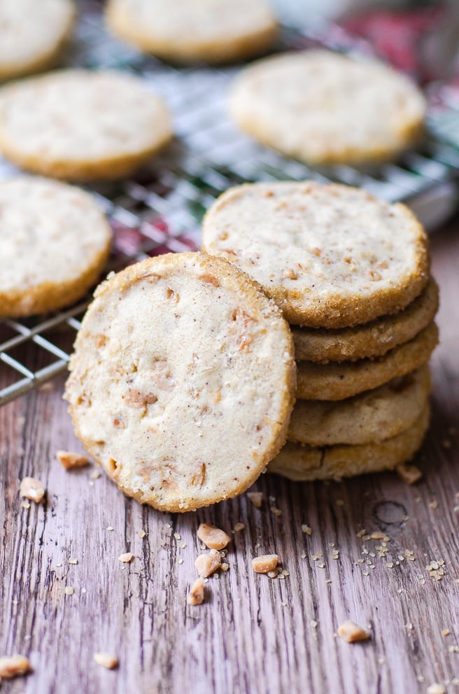 A single round shortbread cookie leaning against a stack of five