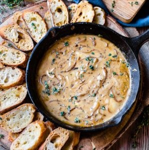 Overhead image of baguette slices surrounding a cast iron pan of caramelized onion dip
