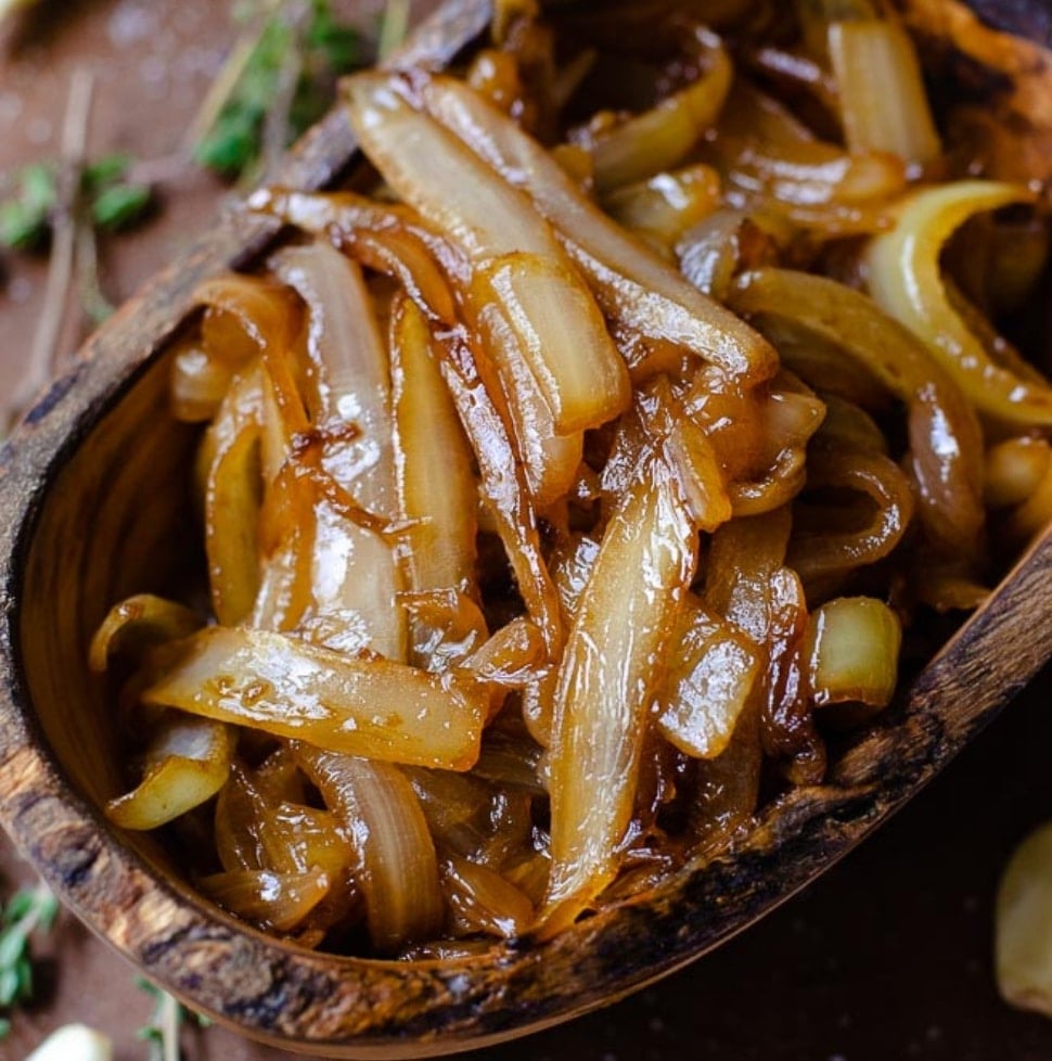 overhead image of a wooden bowl of caramelized onion at an angle