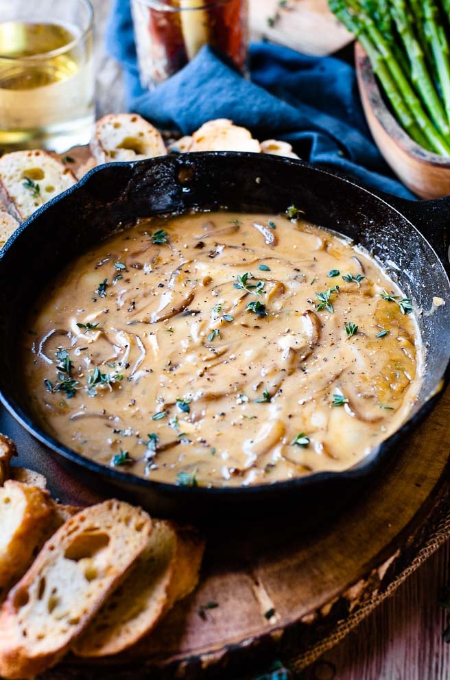 fresh thyme sprinkled on top of brie dip in a cast iron pan