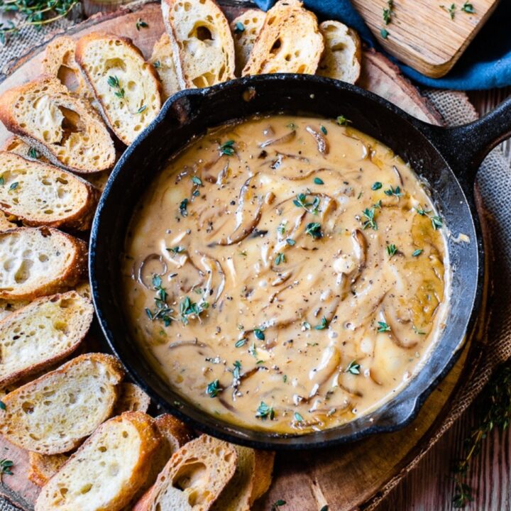 A pan filled with caramelized onion dip and a side of pieces of bread