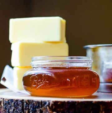 small mason jar of brown butter with three sticks of regular butter stacked behind it