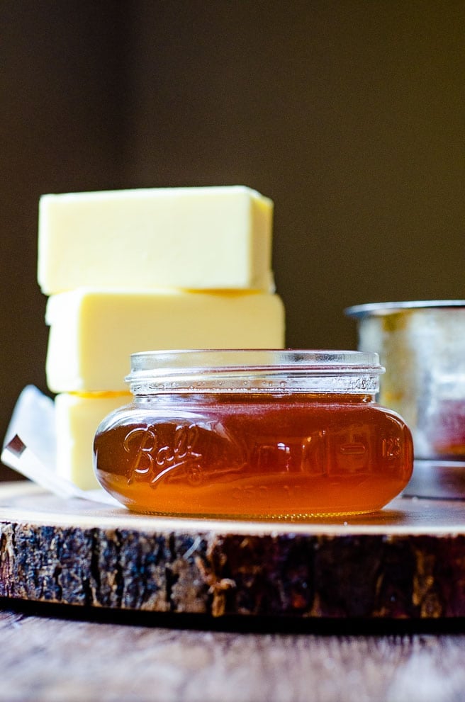 small mason jar of brown butter with three sticks of regular butter stacked behind it