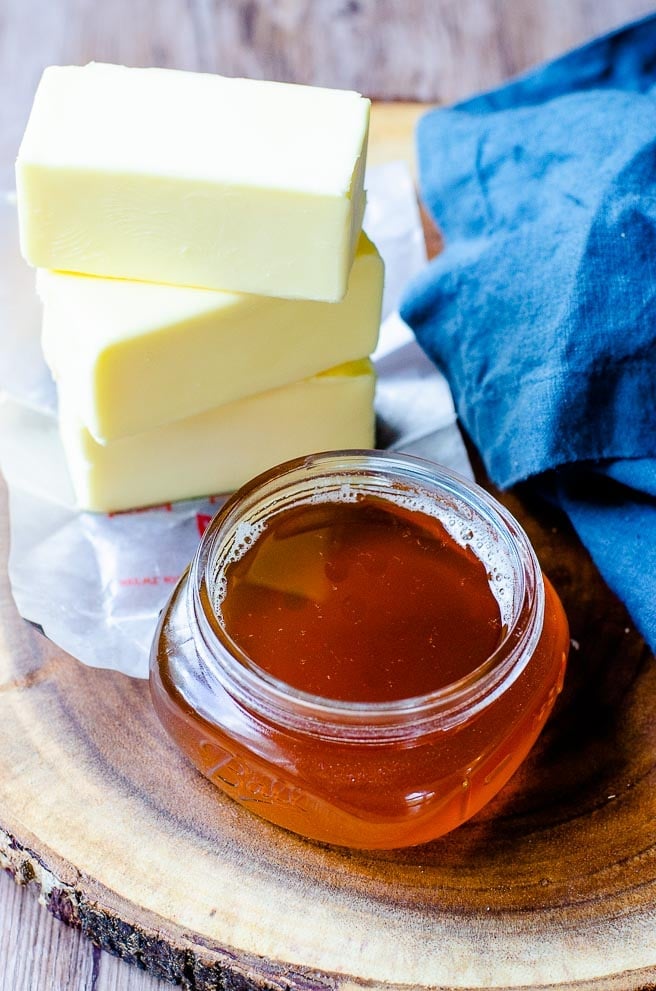 small jar of browned butter next to sticks of regular butter and a blue napkin