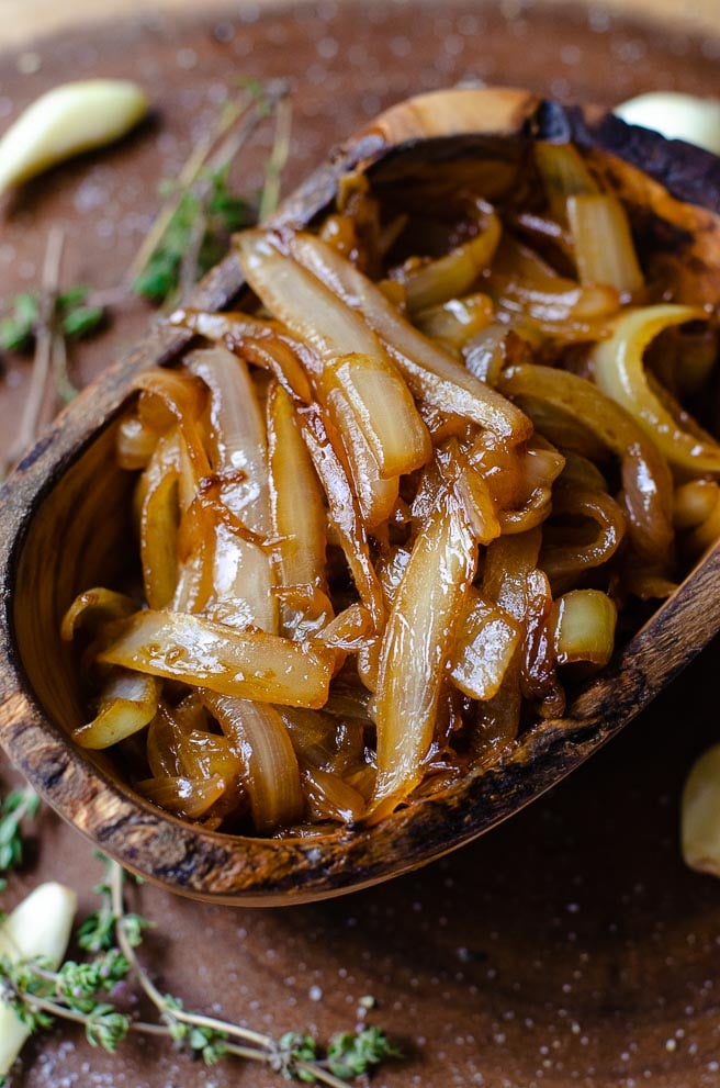A oval shaped wooden bowl of caramelized onions