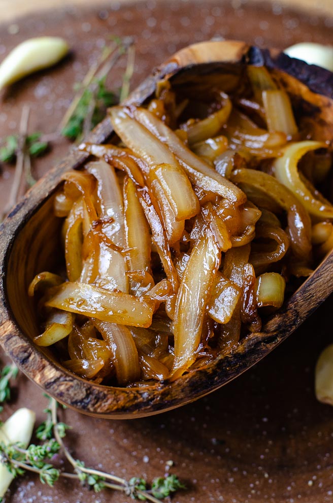 A oval shaped wooden bowl of caramelized onions