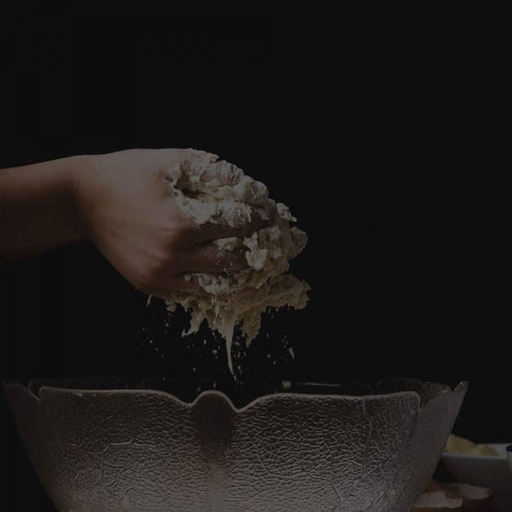 Black overlay on hands pulling dough out of a bowl.