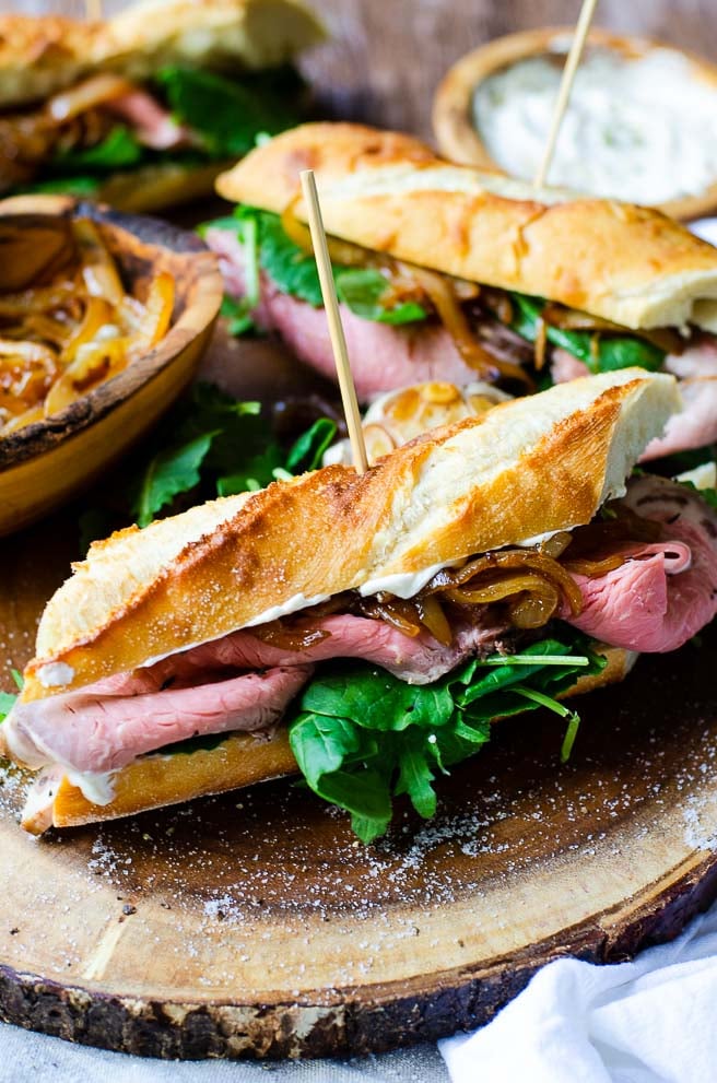 Two assembled prime rib sandwiches on a wooden board