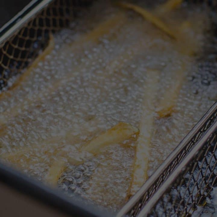 Black overlay on a basket of french fries deep frying in oil.