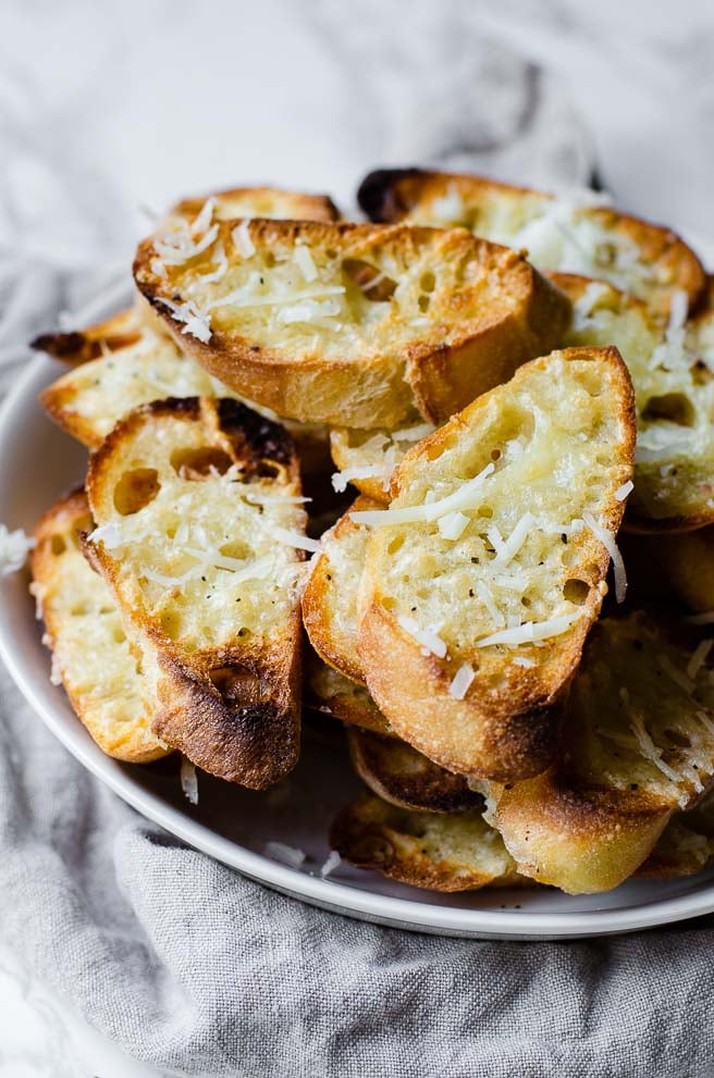 A white bowl filled with homemade garlic toast with cheese on top