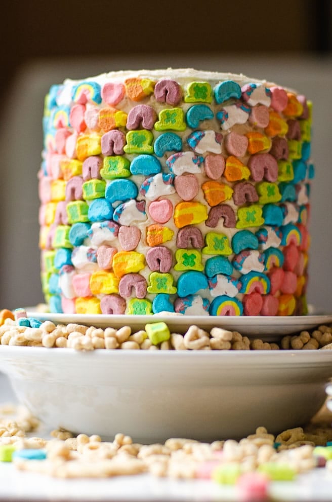 A bowl of lucky charms with a cake stand holding a lucky charms cake in it