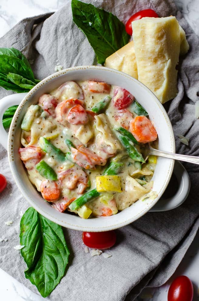 overhead view of a white bowl of lasagna soup surround by soup ingredients