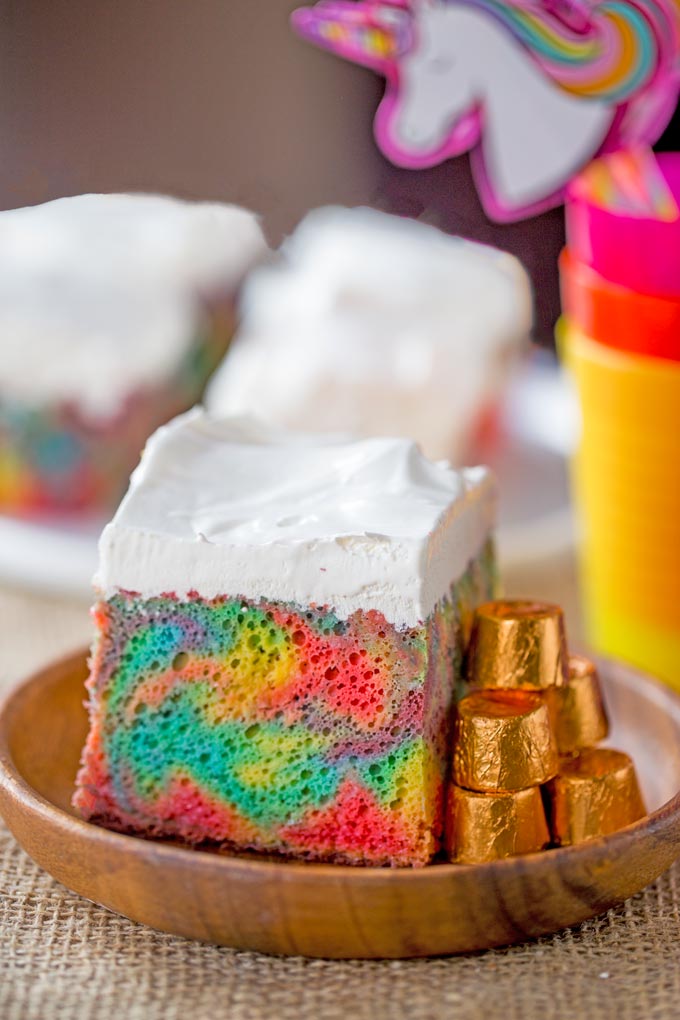 close up of a slice of rainbow poke cake