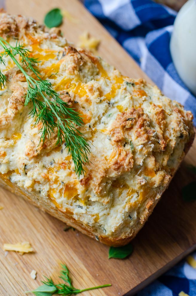 overhead view of a whole loaf of buttermilk quick bread. It is garnished with fresh dill.