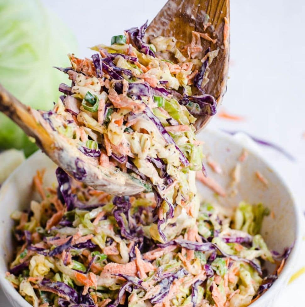 wooden salad tongs lifting up coleslaw.