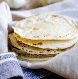 A stack of homemade tortillas in a kitchen towel