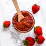 Jar of bbq sauce surrounded by strawberries