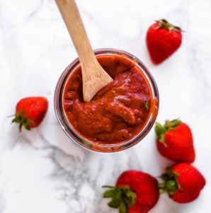 Jar of bbq sauce surrounded by strawberries