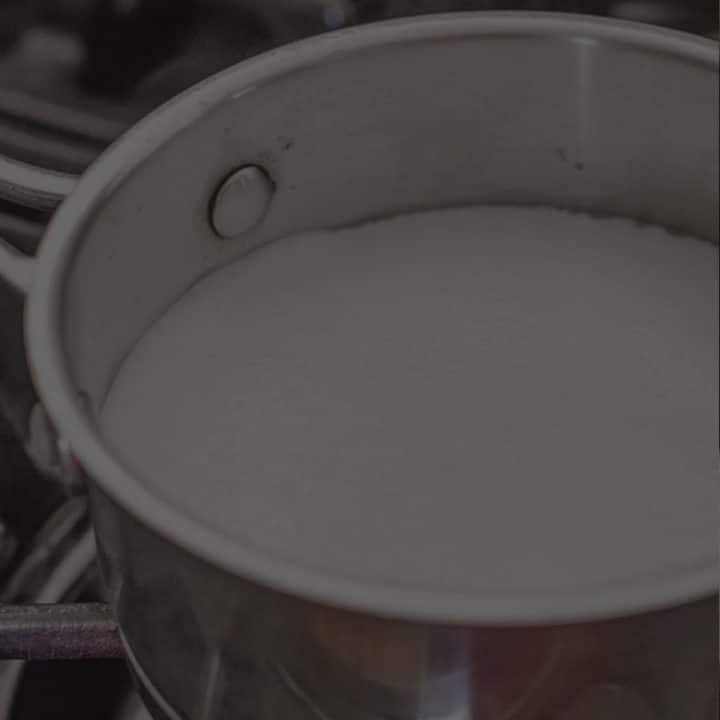 pot of scalded milk on a cooktop with a black overlay.