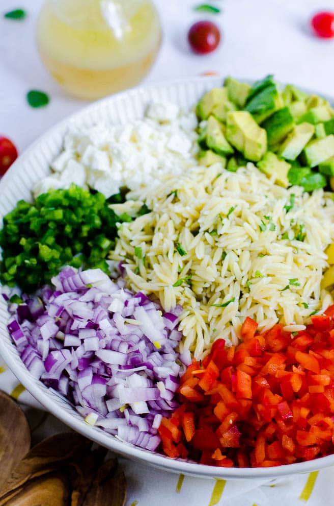 ingredients for pasta salad arranged by color in a bowl.