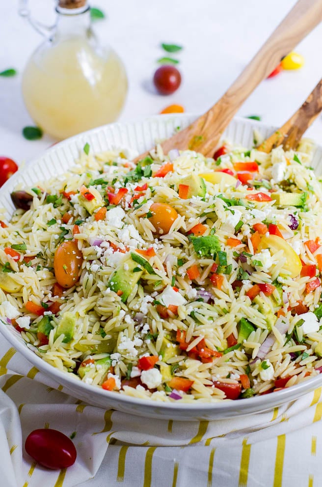 Bowl of orzo pasta salad on a white and gold napkin.