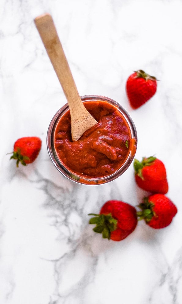 A wooden spoon inside a jar of chipotle bbq sauce.