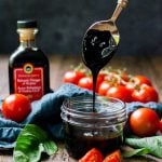 A jar of balsamic reduction with a spoon showing how thick it should be.