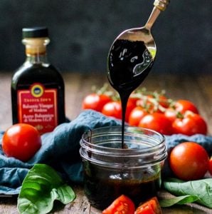 A jar of balsamic reduction with a spoon showing how thick it should be.