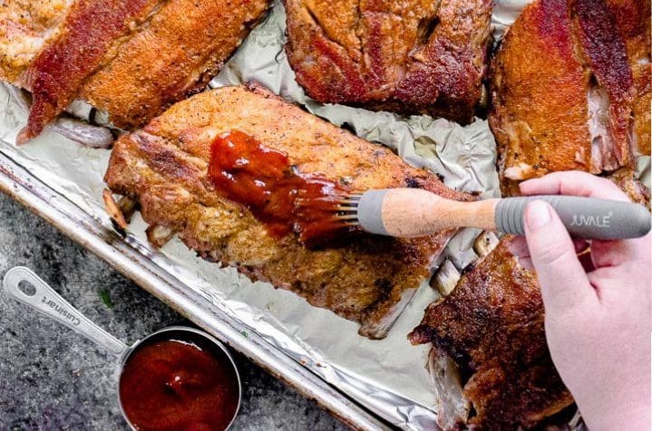 homemade bbq sauce being spread on baby back ribs