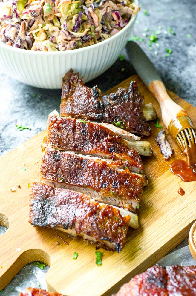 A rack of oven baked ribs cut into slices on a cutting board