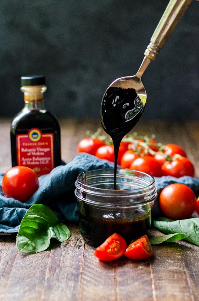 A spoon drizzling a balsamic reduction into a jar