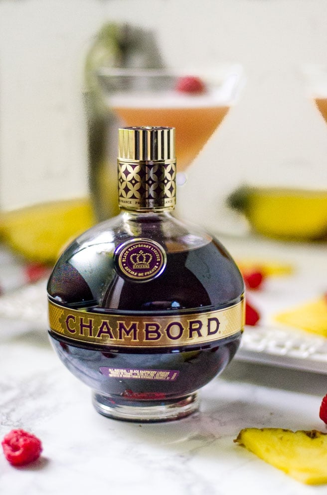 Bottle of Chambord surrounded by fruit garnishes for a cocktail.