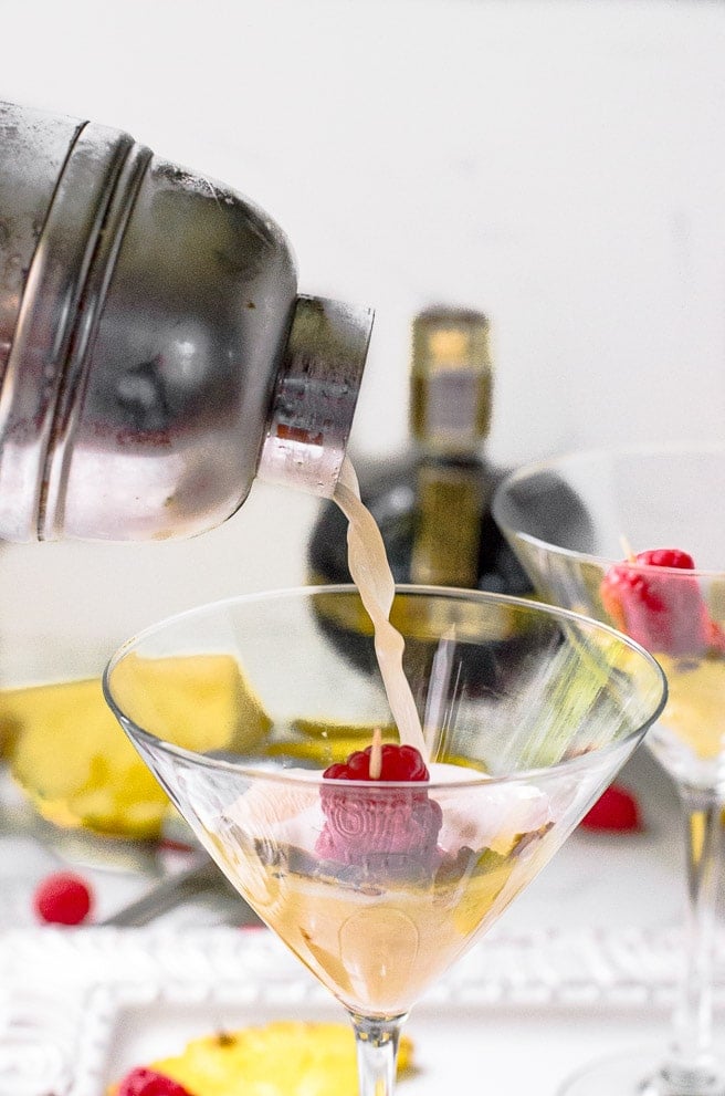 Liquid being poured out of a cocktail shaker into martini glass